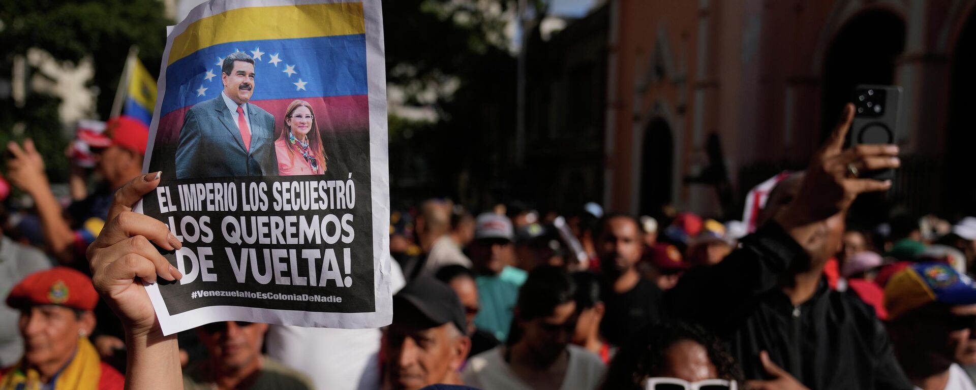 Manifestantes exibem cartazes com os dizeres em espanhol: O império os sequestrou; nós os queremos de volta, durante um protesto exigindo a libertação de Nicolás Maduro e Cilia Flores da custódia dos EUA, em Caracas. Venezuela, 4 de janeiro de 2026 - Sputnik Brasil, 1920, 07.01.2026