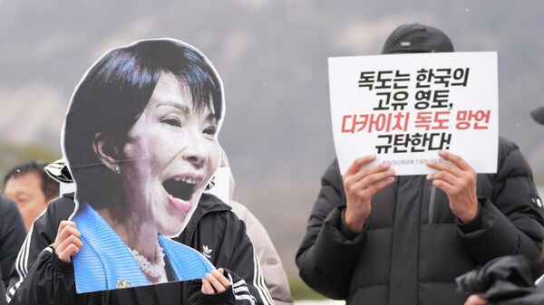 Manifestante segura foto da primeira-ministra japonesa Sanae Takaichi ao lado de um cartaz que diz Dokdo é território da Coreia do Sul e Denunciem o comentário de Takaichi sobre Dokdo durante um protesto antes da cúpula entre a Coreia do Sul e o Japão, em Seul, Coreia do Sul, 12 de janeiro de 2026. - Sputnik Brasil