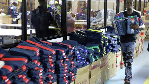 Funcionário de fábrica separa uniformes que serão vendidos no comércio regional. Nairobi, 21 de março de 2025 - Sputnik Brasil