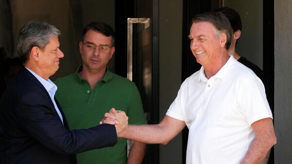 O governador de São Paulo, Tarcísio de Freitas (à esq.), aperta a mão de Jair Bolsonaro (à dir.) em visita à residência do ex-presidente, em Brasília. O senador Flávio Bolsonaro acompanha o cumprimento, em setembro de 2025 - Sputnik Brasil