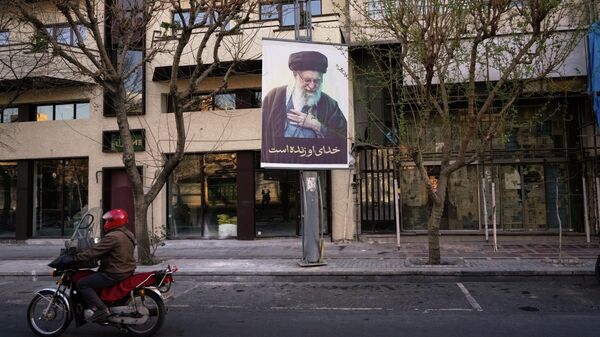 Uma motocicleta passa por uma foto do falecido Líder Supremo iraniano, Aiatolá Ali Khamenei, em uma rua vazia de Teerã, Irã, no domingo, 1º de março de 2026, após a confirmação da morte de Khamenei em ataques dos EUA e de Israel. - Sputnik Brasil
