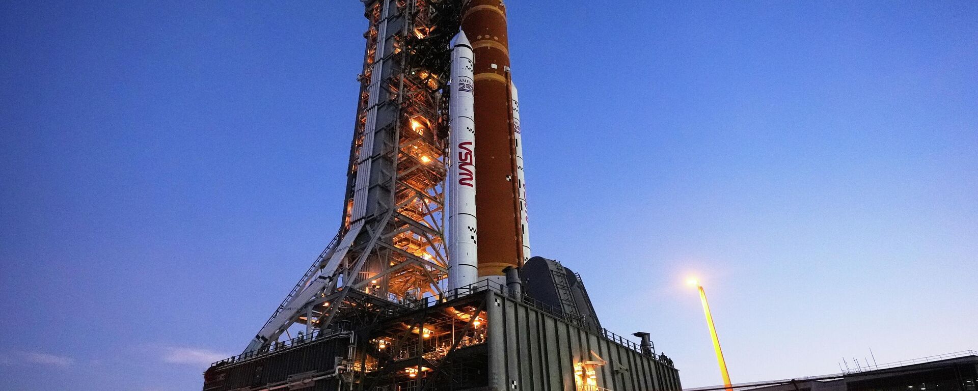 O foguete Artemis II do Sistema de Lançamento Espacial (SLS, na sigla em inglês) da NASA, com a espaçonave Orion a bordo, retorna lentamente em direção ao Edifício de Montagem de Veículos no Centro Espacial Kennedy, em Cabo Canaveral, Flórida, 25 de fevereiro de 2026 - Sputnik Brasil, 1920, 03.03.2026