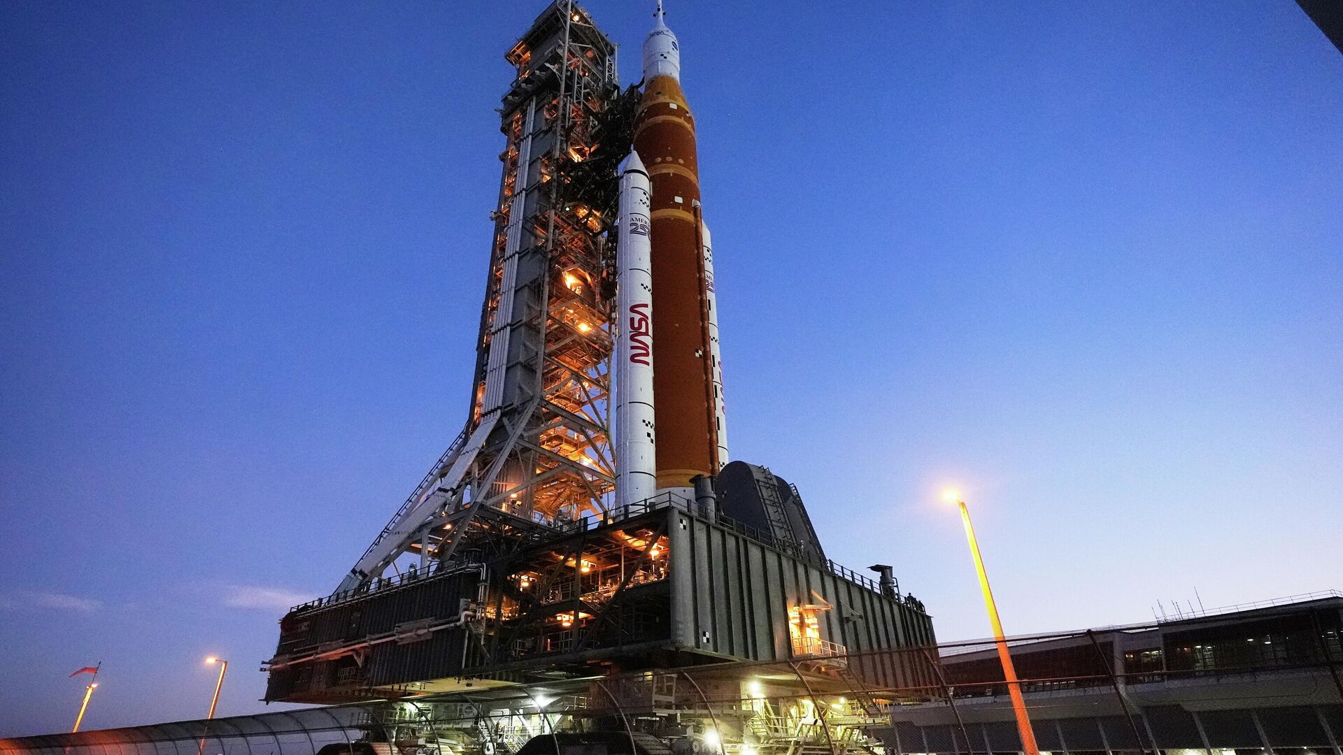 O foguete Artemis II do Sistema de Lançamento Espacial (SLS, na sigla em inglês) da NASA, com a espaçonave Orion a bordo, retorna lentamente em direção ao Edifício de Montagem de Veículos no Centro Espacial Kennedy, em Cabo Canaveral, Flórida, 25 de fevereiro de 2026 - Sputnik Brasil, 1920, 03.03.2026