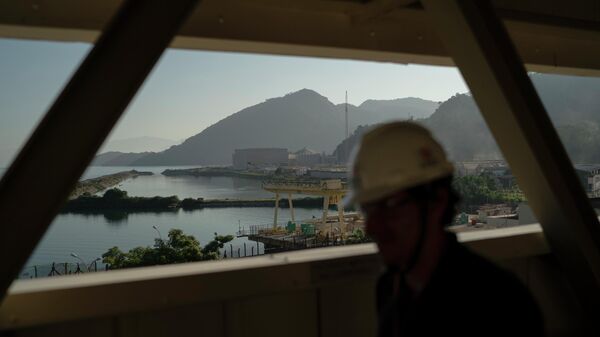 Um funcionário caminha sobre uma passarela de acesso, tendo como pano de fundo o reator nuclear Angra 3, no complexo da Usina Nuclear de Angra. Angra dos Reis, Rio de Janeiro - Sputnik Brasil