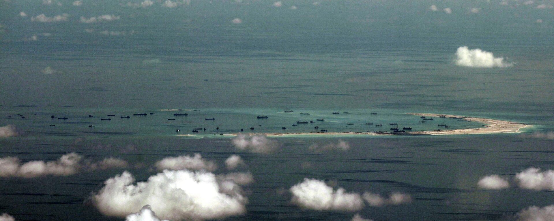 Imagem aérea tirada através da janela de vidro de um avião militar mostra a suposta recuperação em andamento do recife Mischief pela China, nas ilhas Spratly, no mar do Sul da China, 11 de maio de 2015 - Sputnik Brasil, 1920, 23.03.2026