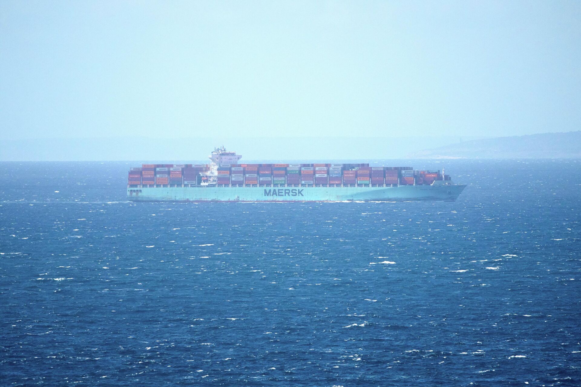 Navio cargueiro trafega próximo à costa do Marrocos pelo Estreito de Gibraltar, em abril de 2025. Ao fundo, o continente europeu - Sputnik Brasil, 1920, 23.03.2026