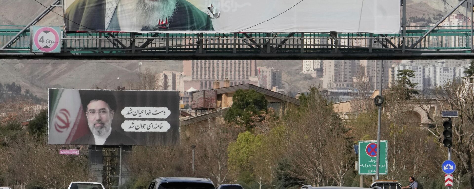 Veículos passam sob outdoors com retratos do falecido Líder Supremo iraniano, o aiatolá Ali Khamenei, em primeiro plano, e de seu filho, o aiatolá Mojtaba Khamenei, seu sucessor, ao longo de uma rodovia em Teerã, no Irã - Sputnik Brasil, 1920, 27.03.2026