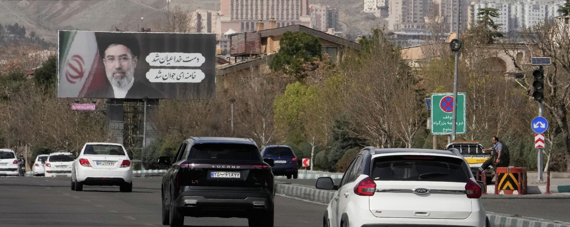 Veículos passam sob outdoors com retratos do falecido Líder Supremo iraniano, o aiatolá Ali Khamenei, em primeiro plano, e de seu filho, o aiatolá Mojtaba Khamenei, seu sucessor, ao longo de uma rodovia em Teerã, no Irã - Sputnik Brasil, 1920, 27.03.2026