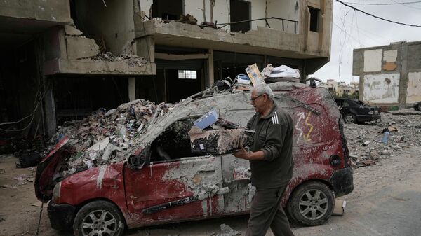 Homem recupera alguns de seus pertences de um prédio destruído em um ataque aéreo israelense anterior, durante um cessar-fogo entre o Hezbollah e Israel no bairro de Hosh, em Tiro, sul do Líbano, em 19 de abril de 2026 - Sputnik Brasil