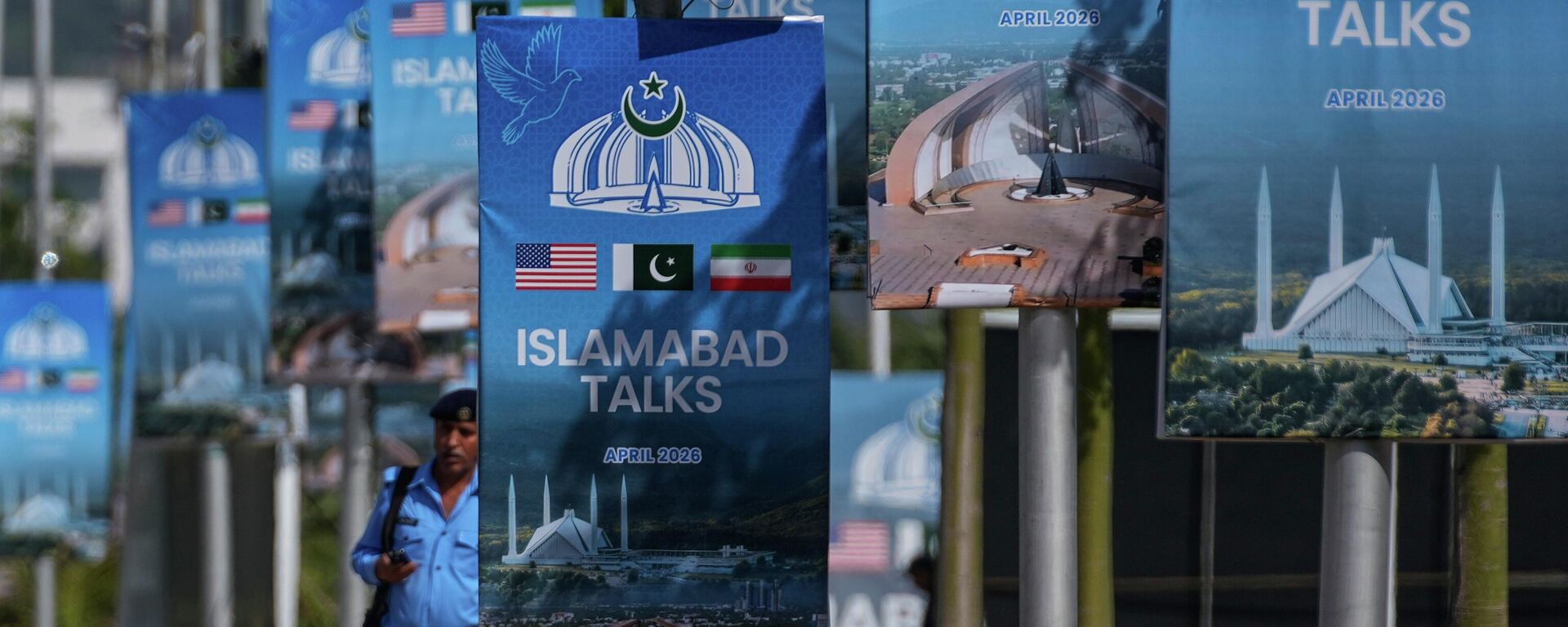 Um policial caminha ao lado de outdoors perto do Hotel Serena, em Islamabad, onde ocorrerá a segunda rodada de negociações entre os EUA e o Irã. Paquistão, 21 de abril de 2026 - Sputnik Brasil, 1920, 21.04.2026