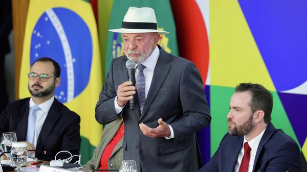 O presidente brasileiro Luiz Inácio Lula da Silva, acompanhado dos ministros do Empreendedorismo, da Microempresa e da Empresa de Pequeno Porte, Paulo Henrique Rodrigues (E), da Casa Civil, Miriam Belchior (atrás de Lula), da Fazenda, Dário Durigan (D) e do Planejamento, Bruno Moretti (fora da imagem), assina Medida Provisória referente ao Novo Desenrola Brasil, Brasília, 4 de maio de 2026 - Sputnik Brasil