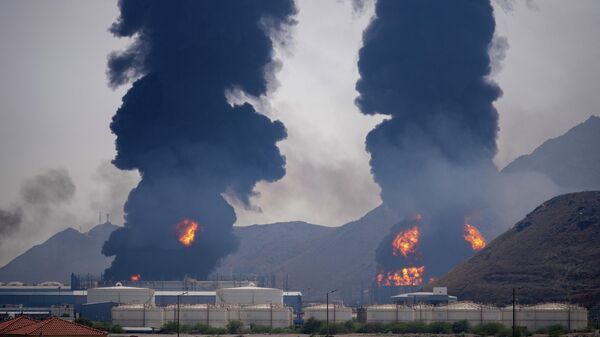 Colunas de fumaça e fogo se elevam após destroços de um drone iraniano interceptado atingirem uma instalação petrolífera, em Fujeira, segundo as autoridades dos Emirados Árabes Unidos, em 14 de março de 2026 - Sputnik Brasil