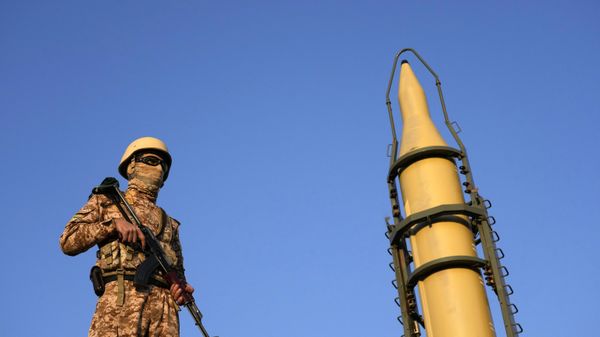Um membro das Forças Armadas iranianas faz a guarda em frente a um míssil de fabricação nacional exibido durante o desfile da força paramilitar Basij em Teerã, Irã, 10 de janeiro de 2025 - Sputnik Brasil