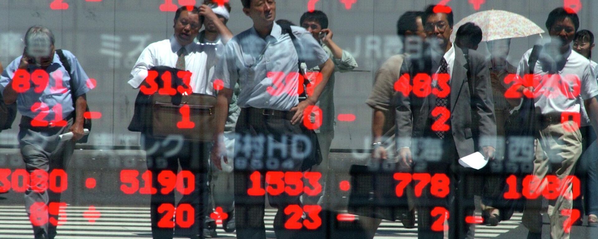 Empresários japoneses são refletidos no painel de cotações da bolsa enquanto atravessam um cruzamento no centro de Tóquio, 9 de agosto de 2002 - Sputnik Brasil, 1920, 12.05.2026