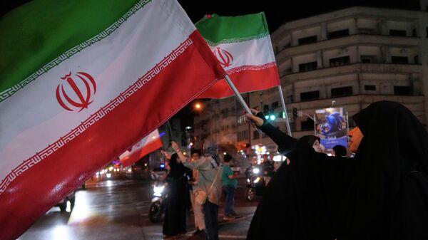 Mulher iraniana segura a bandeira do país em protestos a favor do governo local, em Teerã, em 8 de maio de 2026 - Sputnik Brasil