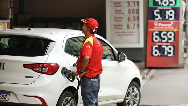 Frentista abastece carro em posto de combustíveis na região central do Rio de Janeiro, em 20 de março de 2026 - Sputnik Brasil