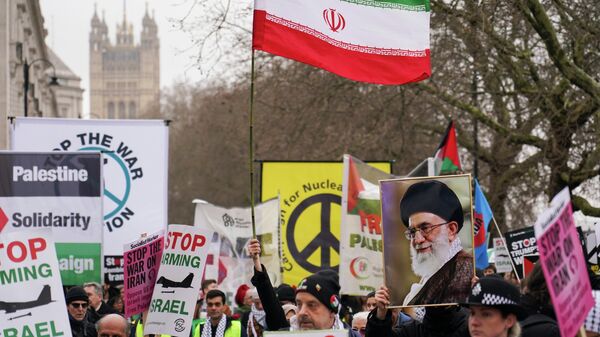 Manifestantes seguram bandeiras e cartazes durante uma marcha da Stop the War Coalition (Coalizão Pare a Guerra) em Londres, 7 de março de 2026 - Sputnik Brasil