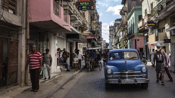 Pessoas caminham sob uma placa que anuncia um supermercado particular, à esquerda, em Havana, Cuba, 11 de novembro de 2023 - Sputnik Brasil