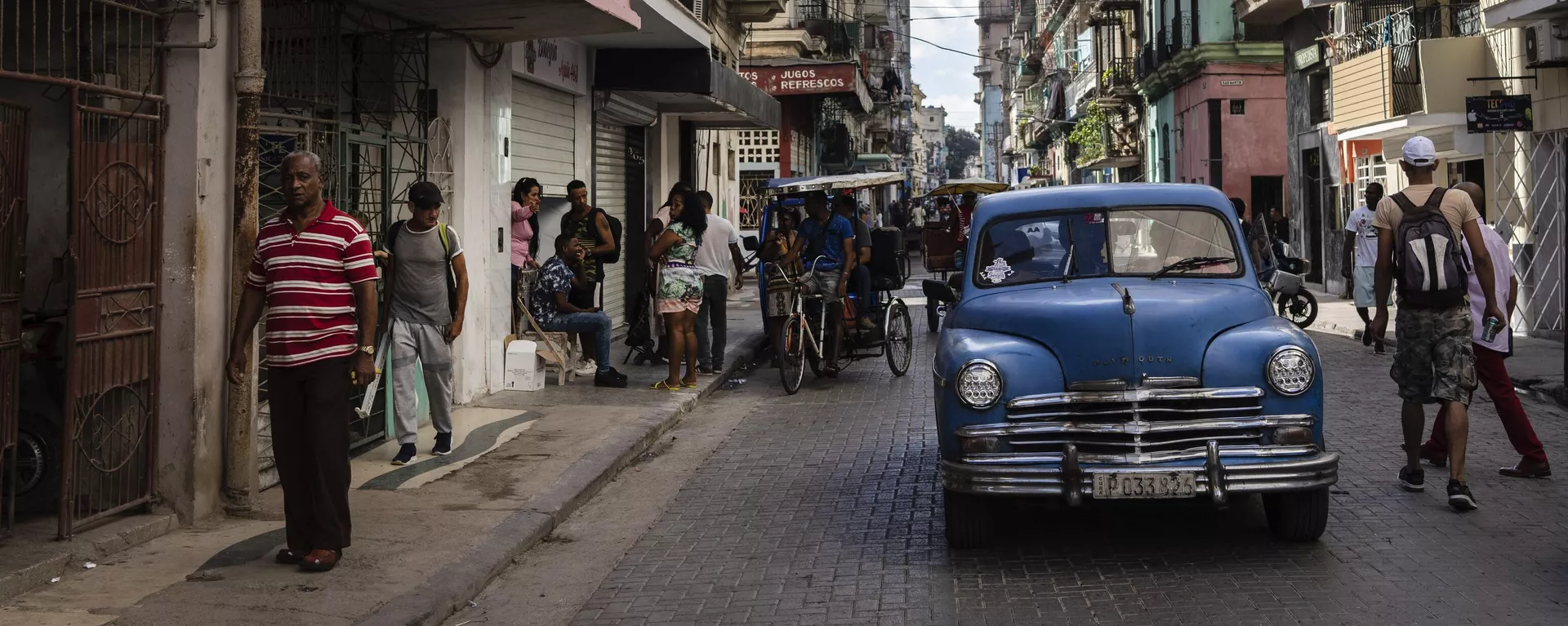 Pessoas caminham sob uma placa que anuncia um supermercado particular, à esquerda, em Havana, Cuba, 11 de novembro de 2023 - Sputnik Brasil, 1920, 06.06.2026