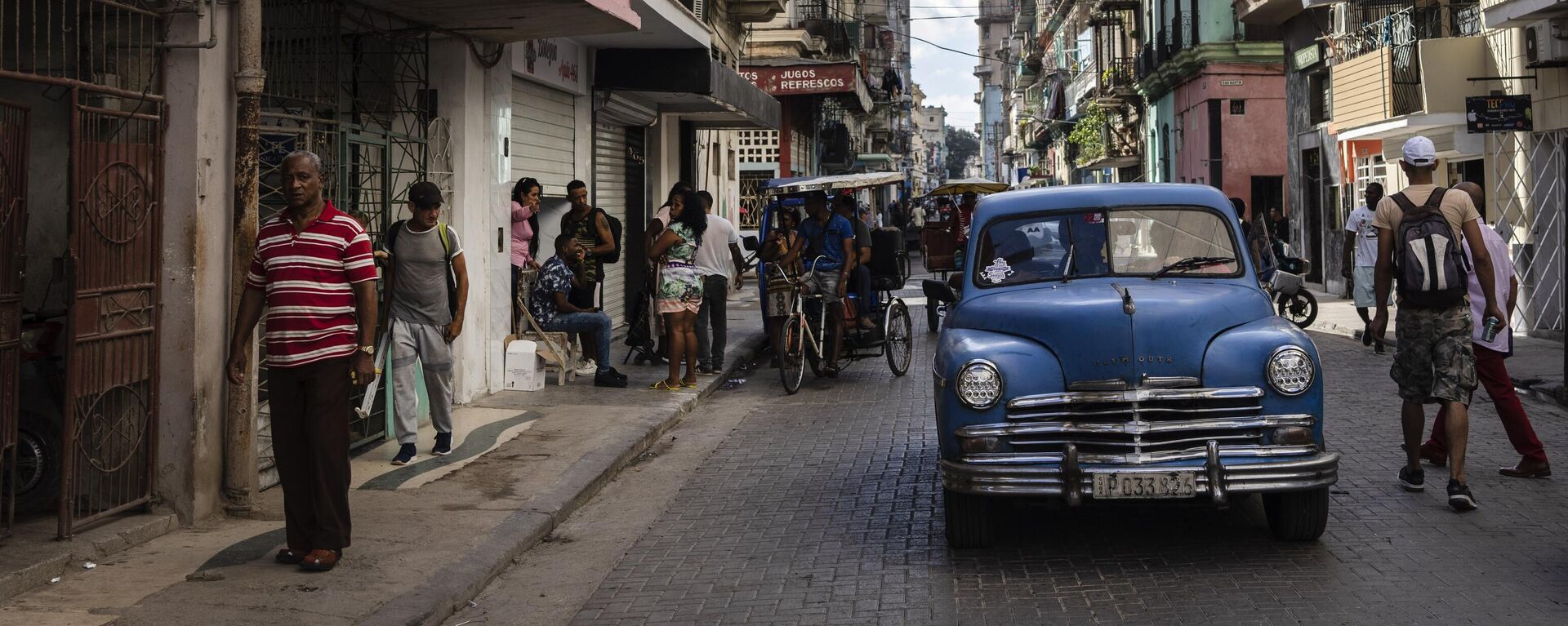 Pessoas caminham sob uma placa que anuncia um supermercado particular, à esquerda, em Havana, Cuba, 11 de novembro de 2023 - Sputnik Brasil, 1920, 04.06.2026