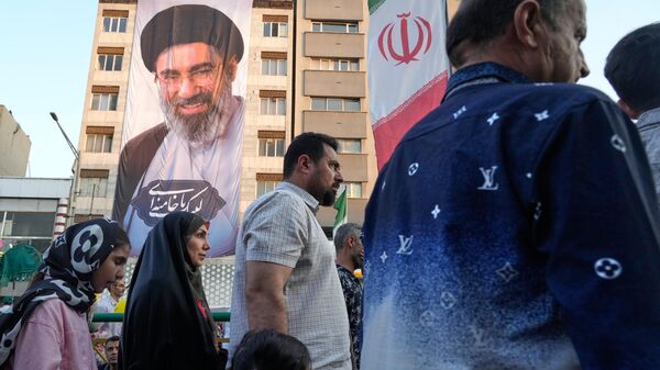 Pessoas marcham sob um retrato do Líder Supremo iraniano, o aiatolá Mojtaba Khamenei, durante um festival de rua que celebra o feriado muçulmano xiita de Eid al-Ghadir, aniversário da nomeação de Ali, sucessor do profeta Maomé, reverenciado como o primeiro imã xiita, em Teerã, 4 de junho de 2026 - Sputnik Brasil