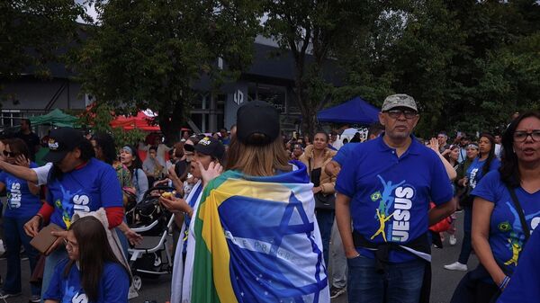 Mulher veste bandeiras de Brasil e Israel mescladas entre si, indumentária comum durante a Marcha para Jesus, em Santana, zona norte de São Paulo, em 4 de junho de 2026 - Sputnik Brasil