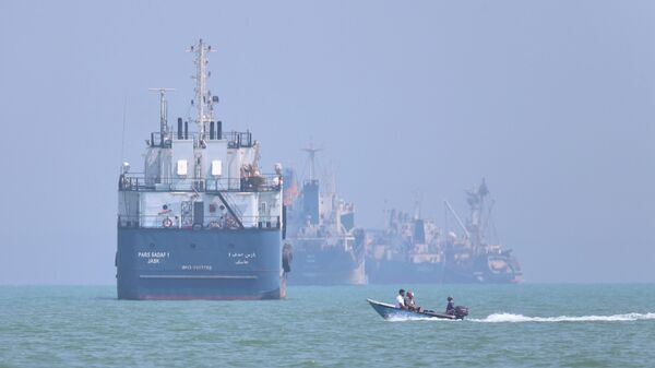 Pequena embarcação passa na frente de um navio no estreito de Ormuz, em Bandar Abbas, em 11 de junho de 2026 - Sputnik Brasil