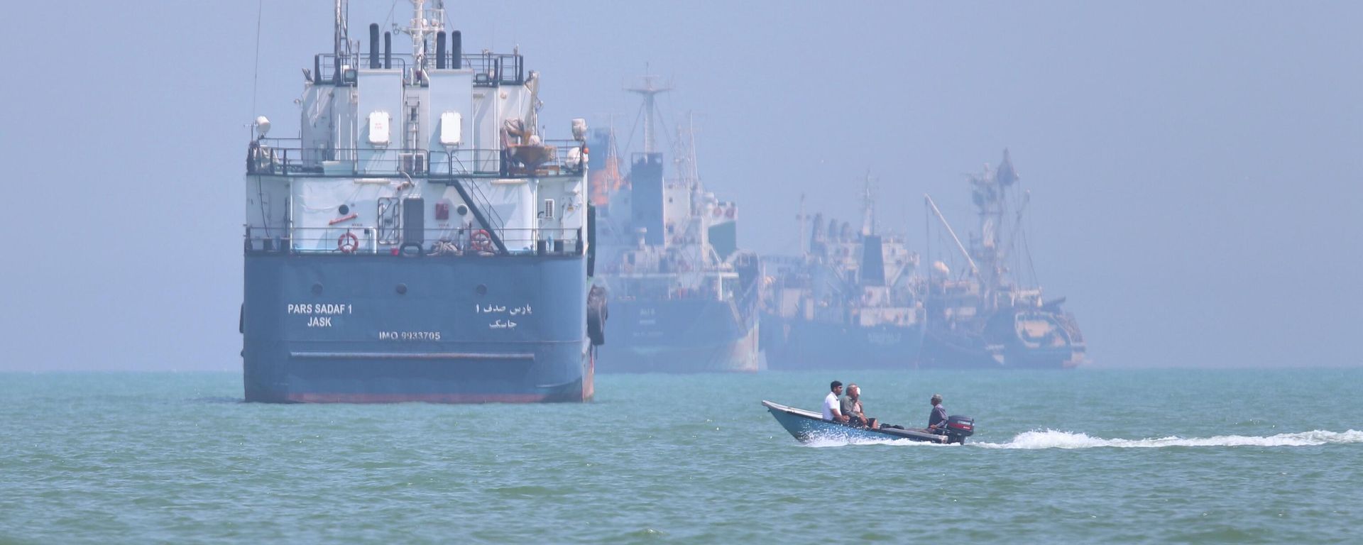 Pequena embarcação passa na frente de um navio no estreito de Ormuz, em Bandar Abbas, em 11 de junho de 2026 - Sputnik Brasil, 1920, 22.07.2026