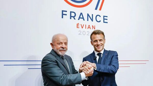 O presidente do Brasil, Luiz Inácio Lula da Silva (à esq.), em aperto de mão com o presidente da França, Emmanuel Macron (à dir.), em encontro em Évian, na França, em 15 de junho de 2026 - Sputnik Brasil