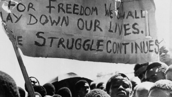 Uma faixa é erguida acima de estudantes negros em Joanesburgo, no bairro de Soweto, onde se reuniram após o funeral de um estudante negro de 16 anos que morreu na prisão. África do Sul, 18 de outubro de 1976 - Sputnik Brasil