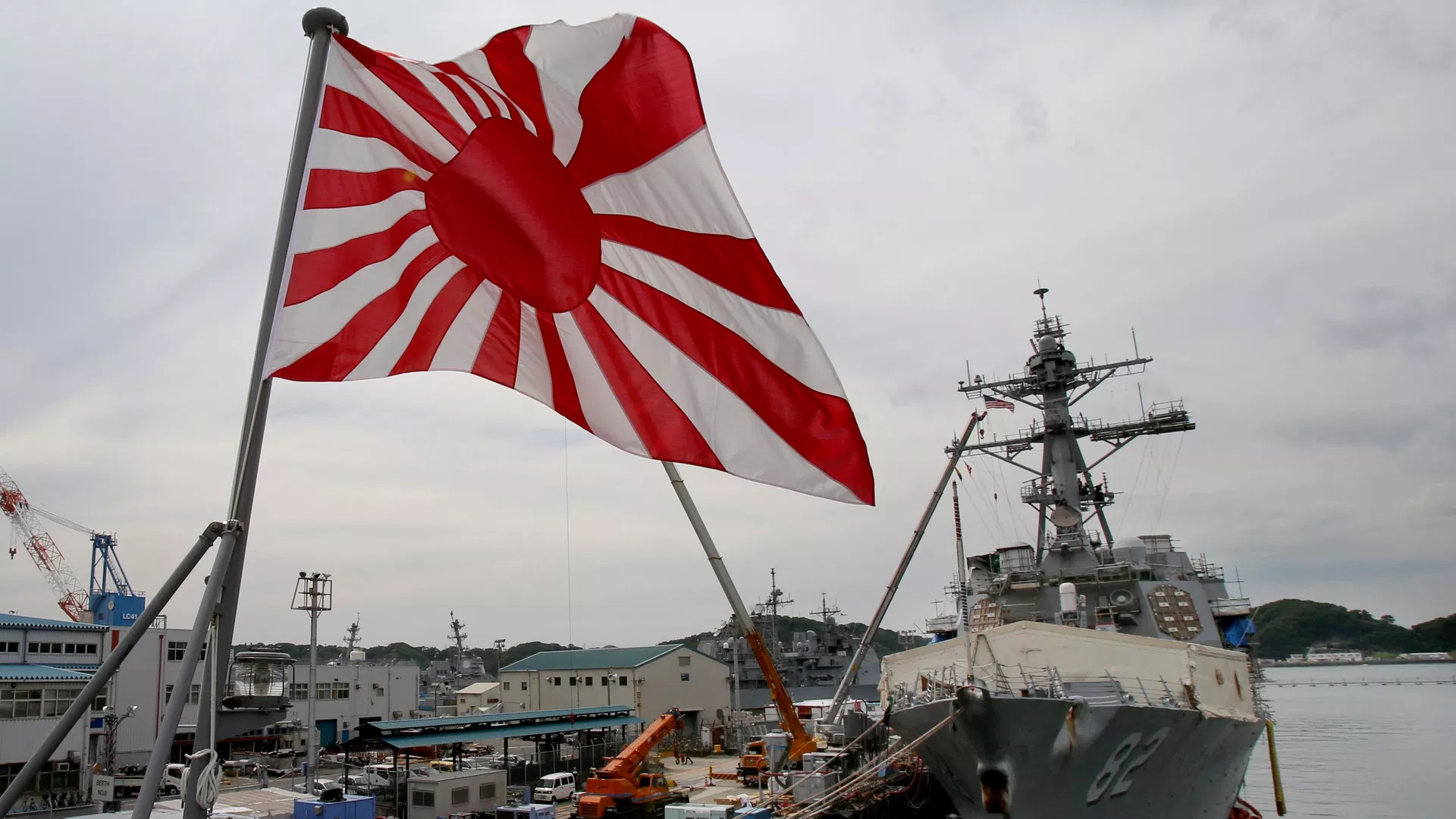 A bandeira militar do Japão — a Bandeira do Sol Nascente — tremula no navio de desembarque de tanques JS Kunisaki, da Força de Autodefesa Marítima do Japão, ancorado em Yokosuka, perto de Tóquio, em 27 de maio de 2014 - Sputnik Brasil, 1920, 25.07.2026