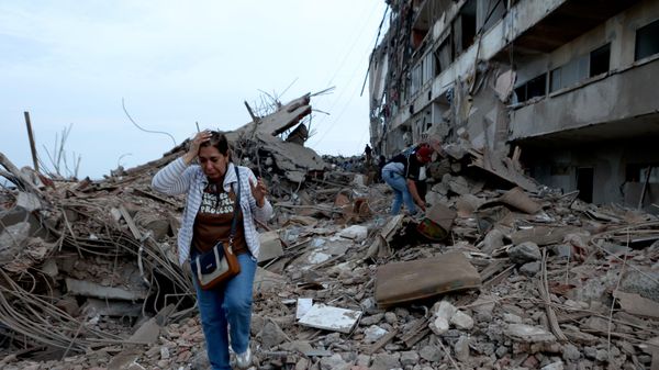 Venezuelanos andam sobre escobros de prédios que desabaram após terremoto, em Catia La Mar, Venezuela, em 25 de junho de 2026 - Sputnik Brasil