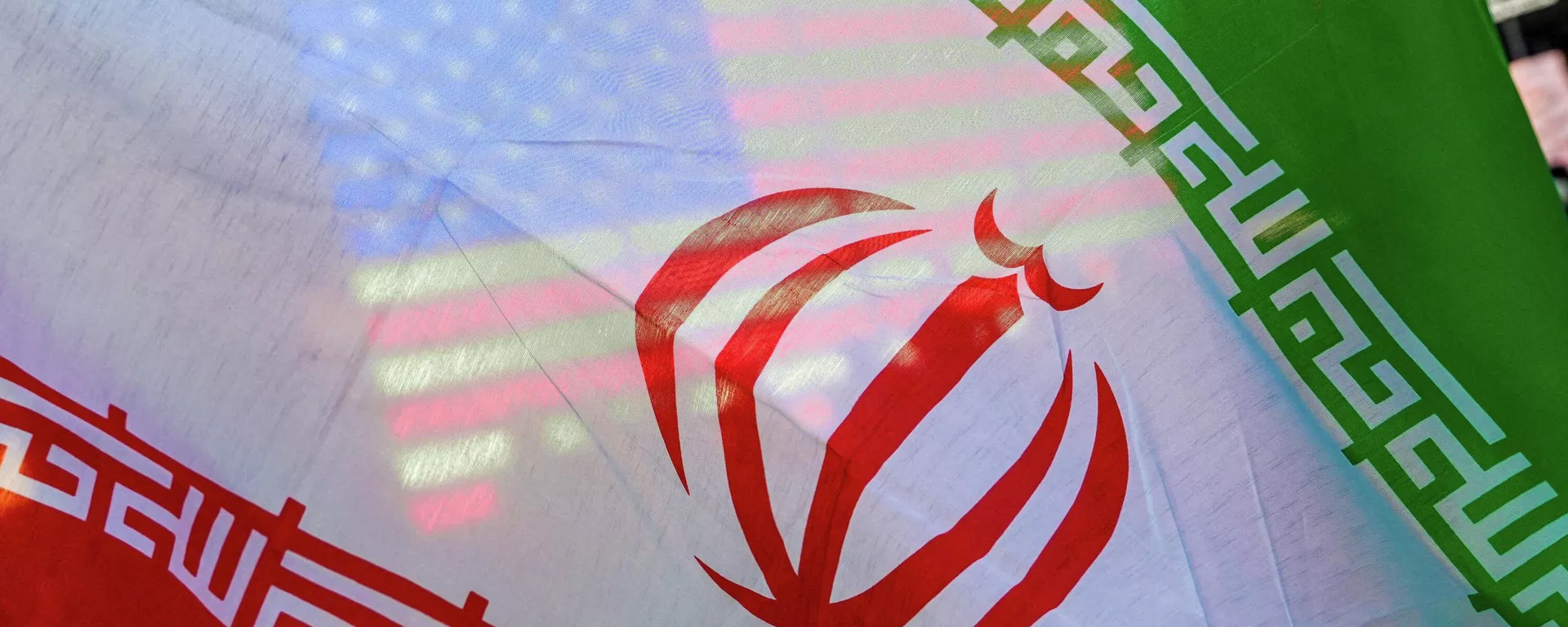 Uma bandeira dos EUA é vista através da bandeira do Irã durante um protesto em Nova York contra a guerra entre EUA e Israel no Irã, 8 de abril de 2026 - Sputnik Brasil, 1920, 15.08.2026