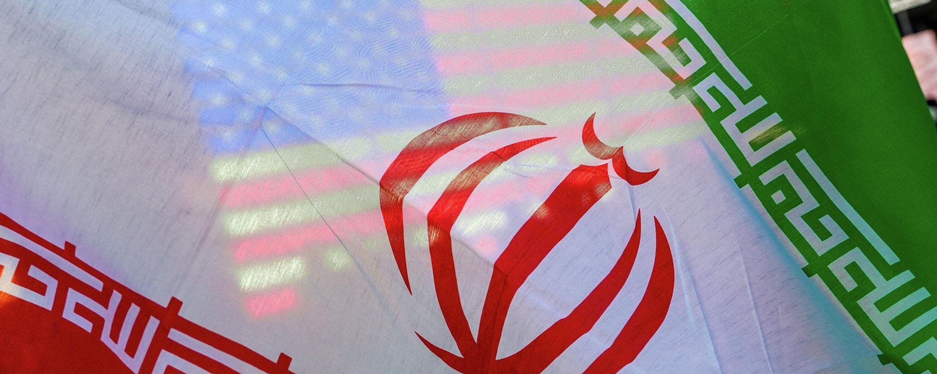 Uma bandeira dos EUA é vista através da bandeira do Irã durante um protesto em Nova York contra a guerra entre EUA e Israel no Irã, 8 de abril de 2026 - Sputnik Brasil, 1920, 17.07.2026
