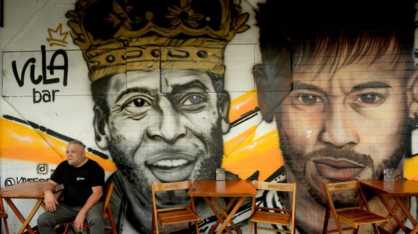 Um homem está sentado diante de um mural da falecida lenda do futebol Pelé e de Neymar em um restaurante em Santos, Brasil - Sputnik Brasil