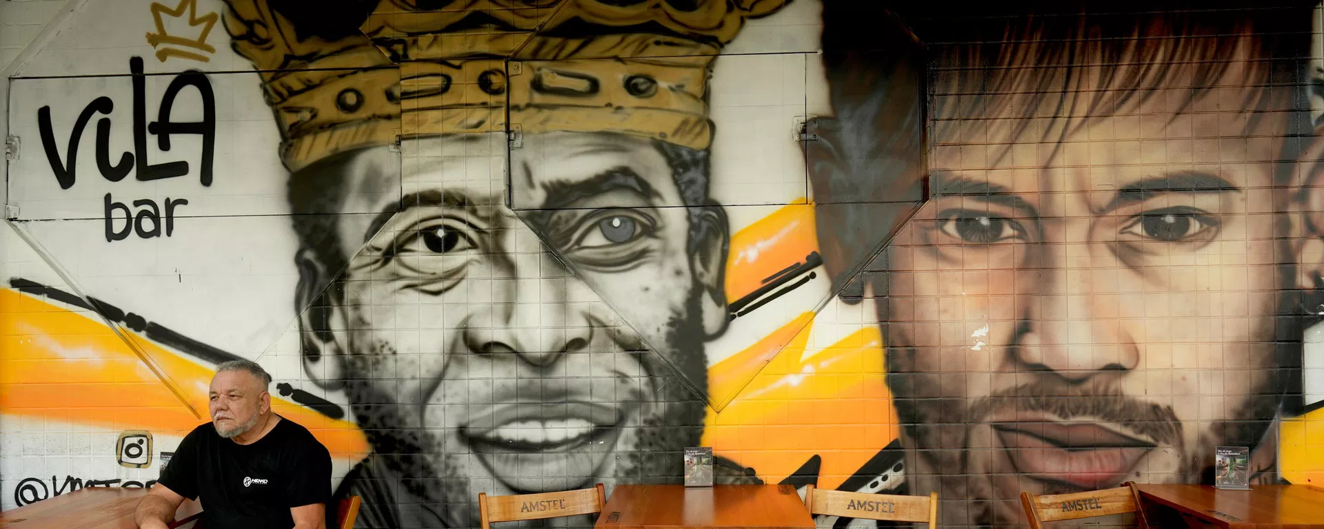 Um homem está sentado diante de um mural da falecida lenda do futebol Pelé e de Neymar em um restaurante em Santos, Brasil Um homem está sentado diante de um mural da falecida lenda do futebol Pelé e de Neymar em um restaurante em Santos, Brasil - Sputnik Brasil, 1920, 06.07.2026