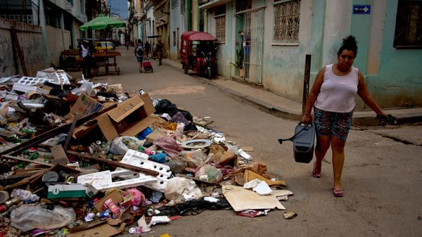 Moradora de Havana passa com água ao lado de pilha de lixo na capital de Cuba, em 6 de julho de 2026 - Sputnik Brasil