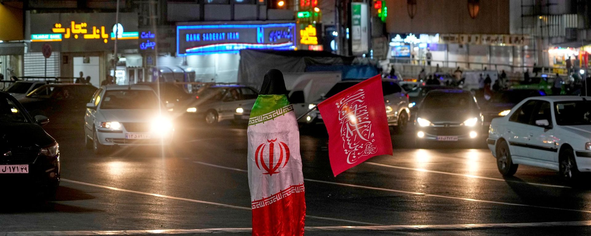 Uma manifestante pró-governo usa uma bandeira do Irã enquanto segura uma bandeira religiosa durante uma concentração em homenagem ao falecido líder supremo iraniano, aiatolá Ali Khamenei, em uma praça de Teerã, Irã, em 11 de julho de 2026 - Sputnik Brasil, 1920, 11.07.2026