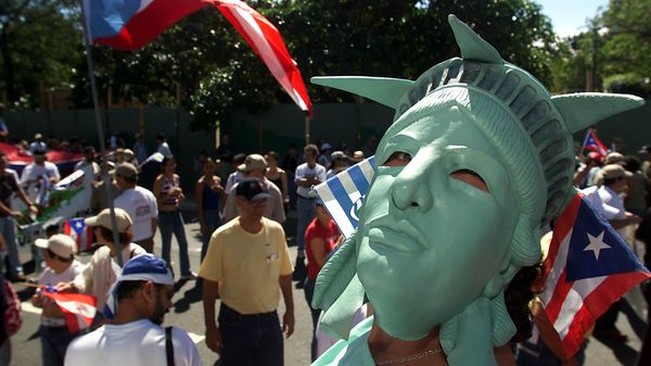 Um manifestante pela paz olha através de uma máscara da Estátua da Liberdade, que traz as bandeiras de Porto Rico e da cidade insular de Vieques adornando sua coroa, em 12 de janeiro de 2003 Um manifestante pela paz olha através de uma máscara da Estátua da Liberdade, que traz as bandeiras de Porto Rico e da cidade insular de Vieques adornando sua coroa, em 12 de janeiro de 2003 - Sputnik Brasil