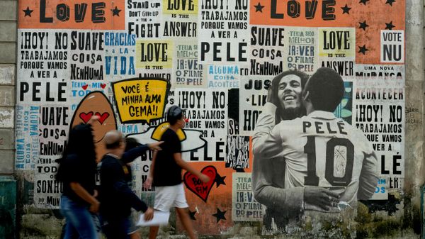 Pessoas passam diante de um mural da falecida lenda do futebol Pelé e do cantor de reggae Bob Marley, em Santos, Brasil. - Sputnik Brasil