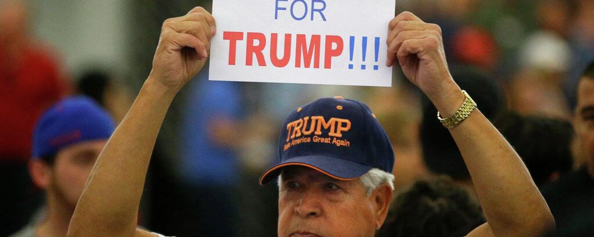 Homem segura uma placa para o então candidato republicano à presidência, Donald Trump, antes do início de um comício no Centro de Convenções de Anaheim, Califórnia, 25 de maio de 2016 - Sputnik Brasil, 1920, 22.07.2026