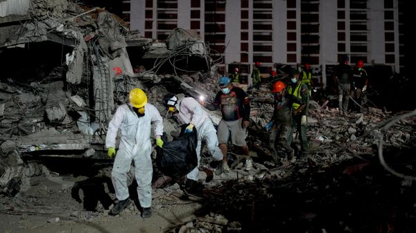 Equipes carregam corpo de pessoa resgatada nos escombros de prédio que colapsou após terremoto em La Guaira, na Venezuela, em 30 de julho de 2026 - Sputnik Brasil