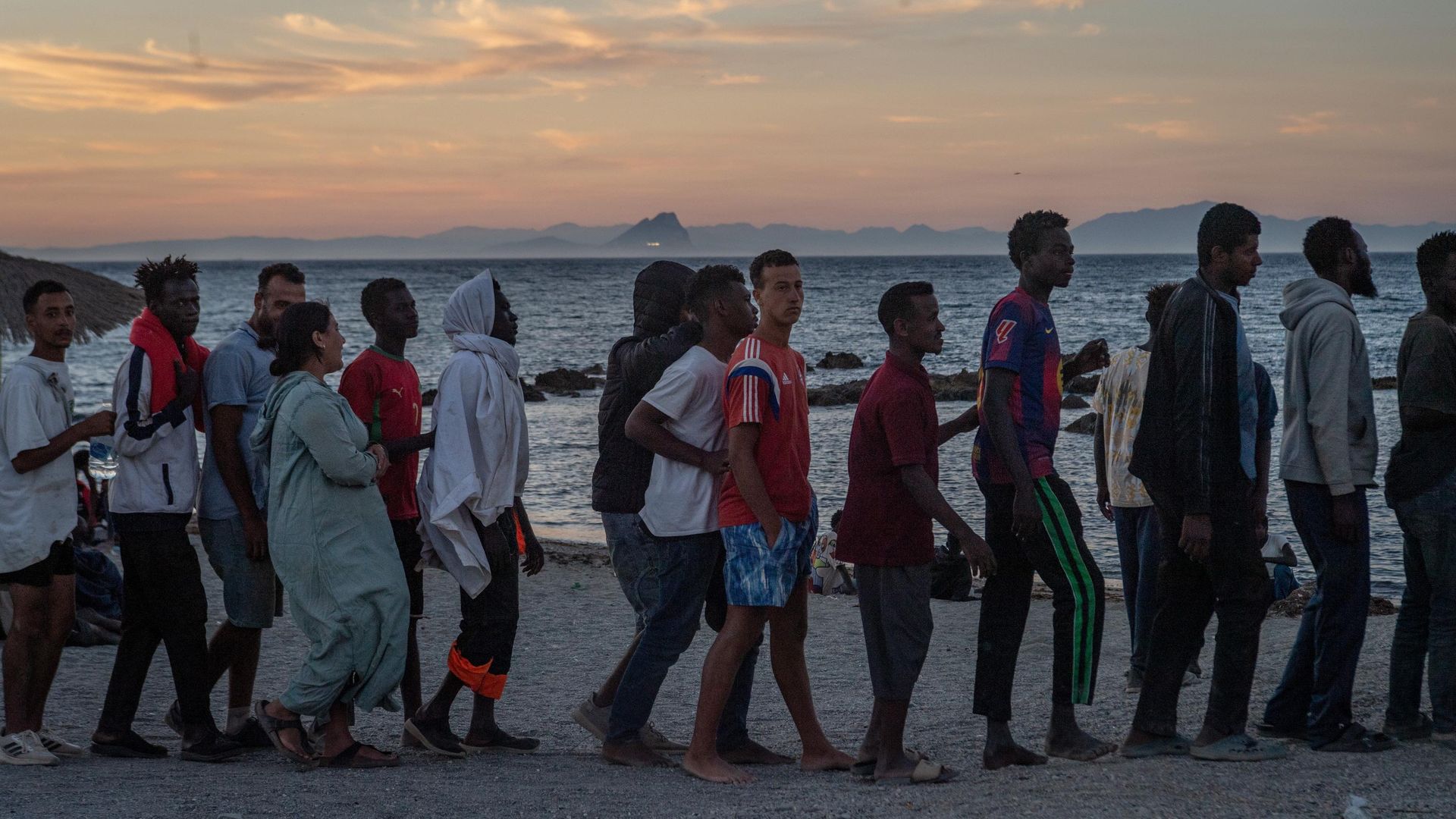 Migrantes que cruzaram a fronteira de Marrocos para a Espanha fazem fila para receber distribuição de alimentos em uma praia no enclave espanhol de Ceuta, 3 de agosto de 2026 Migrantes que cruzaram a fronteira de Marrocos para a Espanha fazem fila para receber distribuição de alimentos em uma praia no enclave espanhol de Ceuta, 3 de agosto de 2026 - Sputnik Brasil, 1920, 17.08.2026
