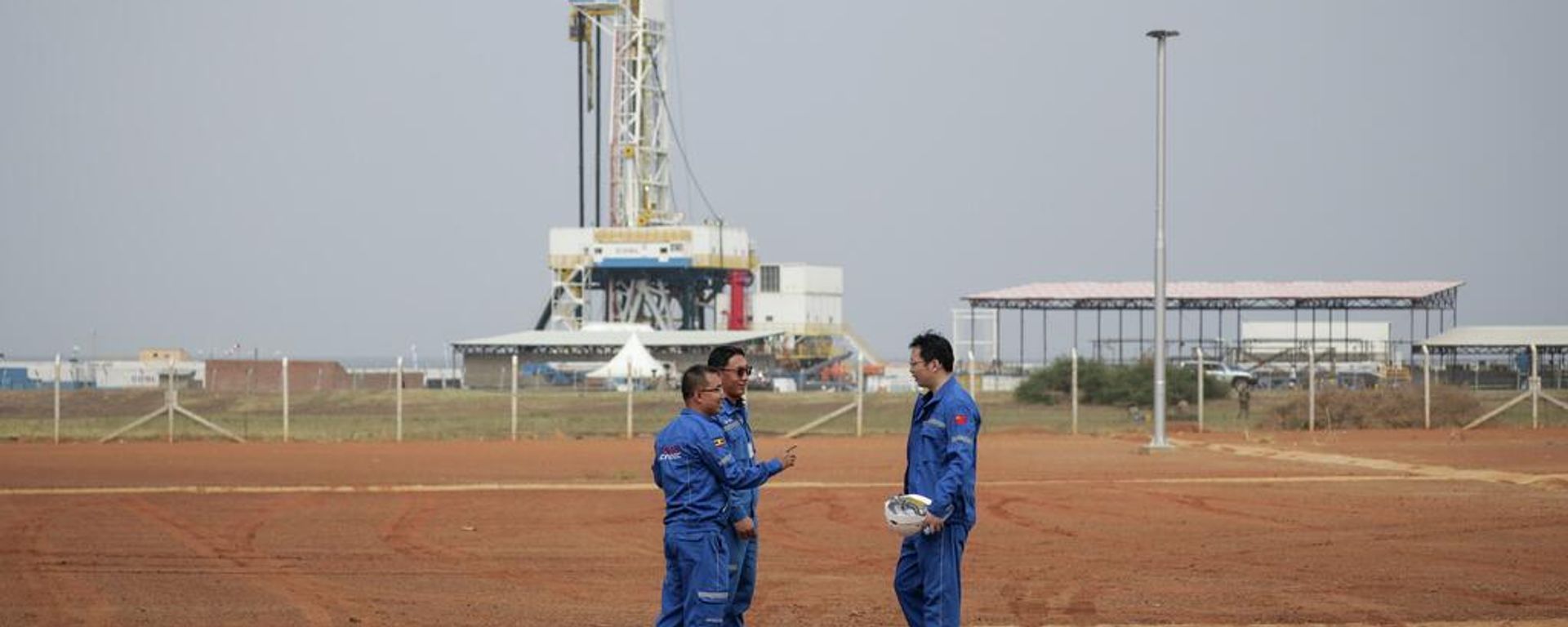 Trabalhadores chineses da Corporação Nacional de Petróleo Offshore da China (CNOOC, na sigla em inglês) posam em frente à plataforma de perfuração no campo petrolífero de Kingfisher, às margens do Lago Albert, no distrito de Kikuube, oeste de Uganda, 24 de janeiro de 2023 Trabalhadores chineses da Corporação Nacional de Petróleo Offshore da China (CNOOC, na sigla em inglês) posam em frente à plataforma de perfuração no campo petrolífero de Kingfisher, às margens do Lago Albert, no distrito de Kikuube, oeste de Uganda, 24 de janeiro de 2023 - Sputnik Brasil, 1920, 18.08.2026