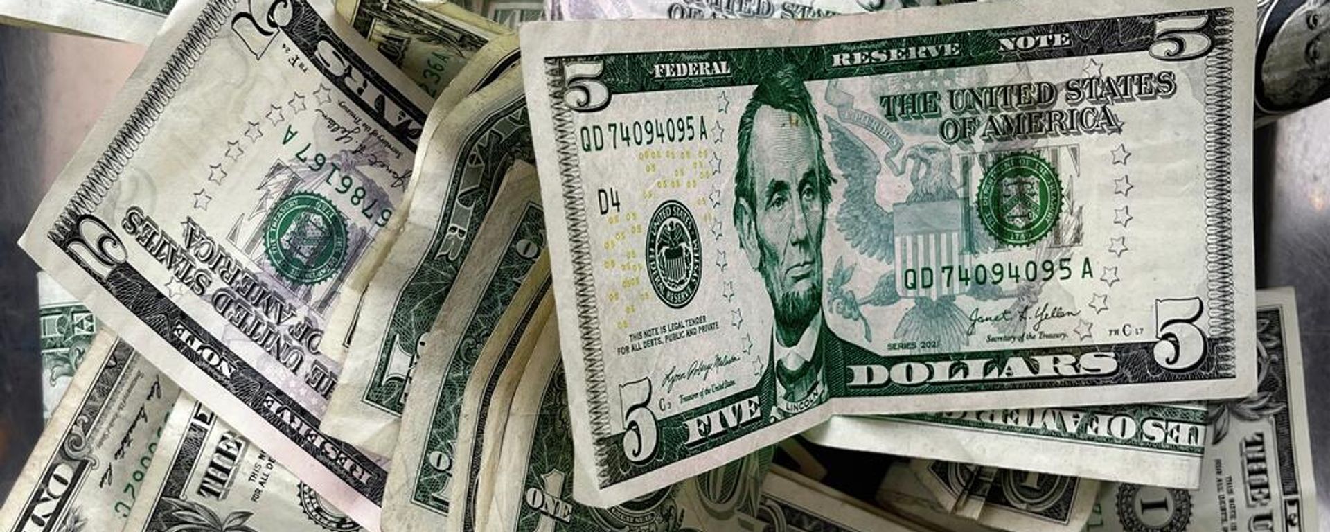 Notas de um e cinco dólares americanos depositadas em uma caixa de gorjetas em um lava-rápido no Brooklyn, Nova York, 17 de dezembro de 2025 - Sputnik Brasil, 1920, 28.08.2026