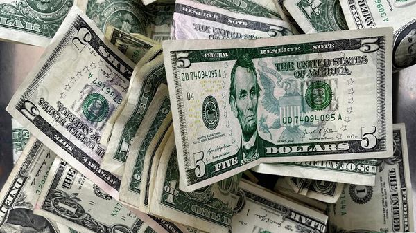 Notas de um e cinco dólares americanos depositadas em uma caixa de gorjetas em um lava-rápido no Brooklyn, Nova York, 17 de dezembro de 2025 - Sputnik Brasil