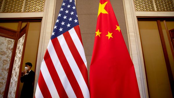 Um funcionário usando máscara passa por bandeiras dos Estados Unidos e da China, posicionadas antes de uma reunião entre a secretária do Tesouro, Janet Yellen, e o vice-primeiro-ministro chinês, He Lifeng, na Casa de Hóspedes de Estado de Diaoyutai, em Pequim, China, 8 de julho de 2023 - Sputnik Brasil