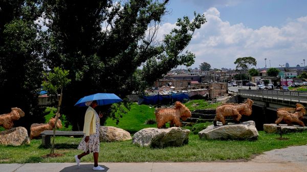 Uma mulher passa por uma série de esculturas feitas com detritos retirados do rio Jukskei, no bairro de Alexandra, em Joanesburgo, África do Sul - Sputnik Brasil