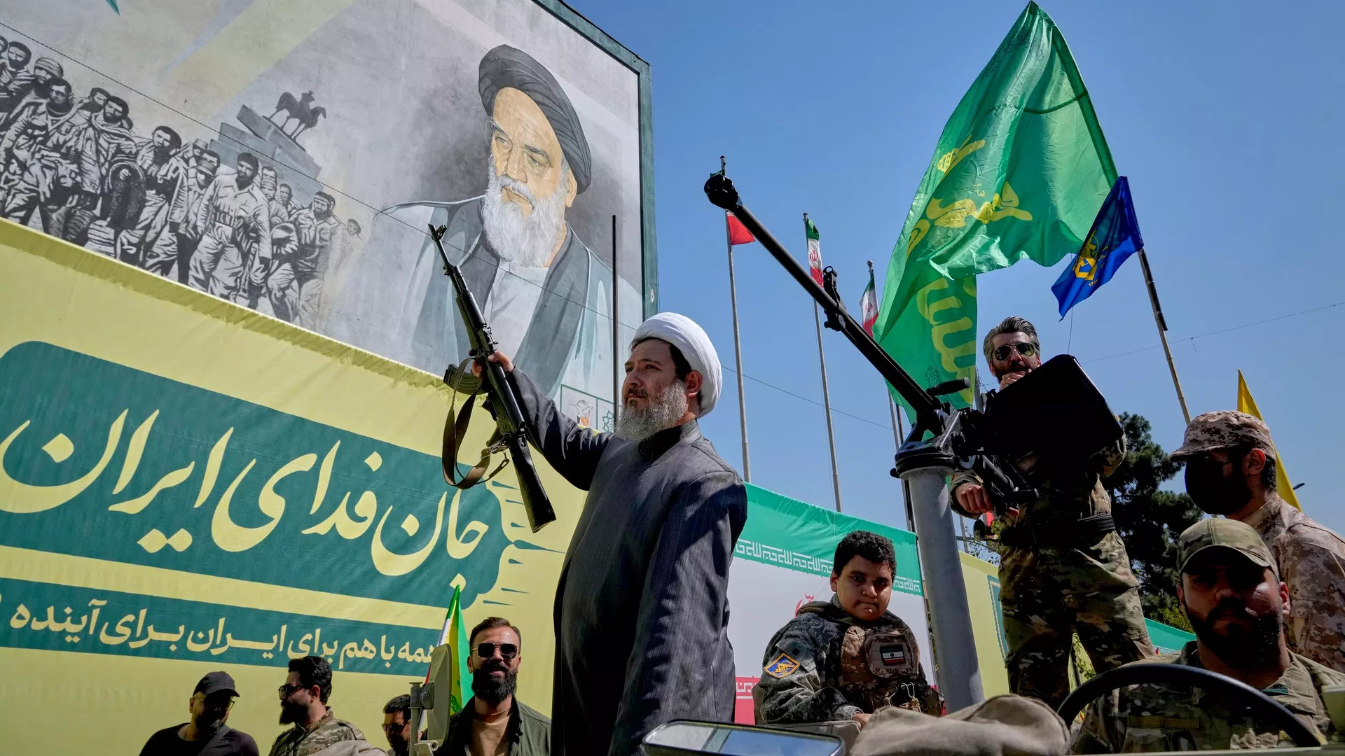 Um clérigo xiita armado passa, a bordo de um veículo militar, por um painel que retrata o aiatolá Ruhollah Khomeini, fundador da República Islâmica do Irã, durante o desfile de estilo militar Janfada — ou Sacrifício pelo Irã —, organizado pelo Estado em Teerã, Irã, em 18 de setembro de 2026 - Sputnik Brasil, 1920, 20.09.2026