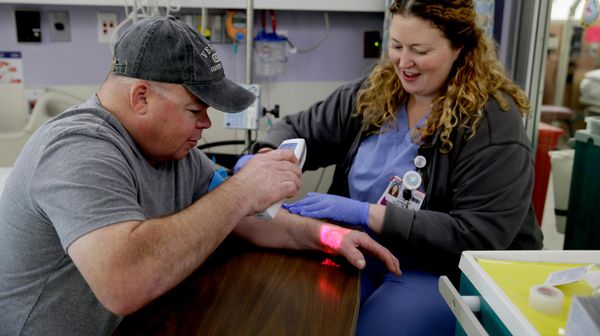 Brian Madeux, de 44 anos, usa um dispositivo infravermelho para visualizar suas veias enquanto a enfermeira Siobhan Field prepara um acesso intravenoso para a primeira terapia de edição genética em humanos, no UCSF Benioff Children's Hospital Oakland, em Oakland, Califórnia, 6 de novembro de 2017 - Sputnik Brasil